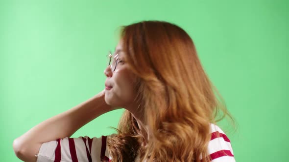 Young woman enjoying strawberry in studio with green screen chroma key background.