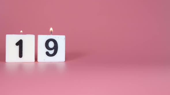 A square candle saying the number 19 being lit and blown out