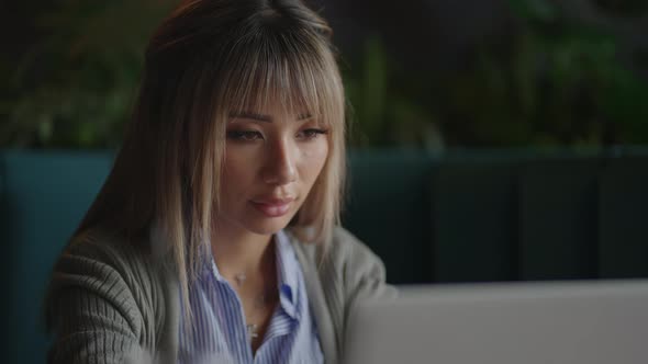 Young Beautiful Smiling Asian Business Woman Holding a Coffee and Laptop Placed at the Wooden Table