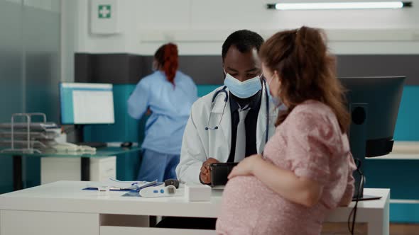 General Practitioner Using Digital Tablet at Appointment with Pregnant Woman