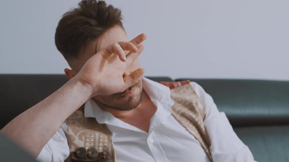 Portrait of Sad Depressed Handsome Man Sitting on the Couch Leaning Head Over His Hand