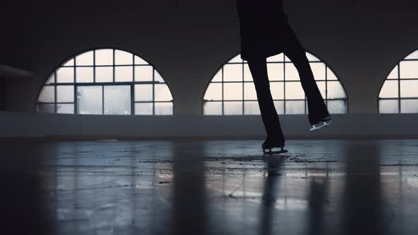 Young Woman is Skating on Dark Ice Arena