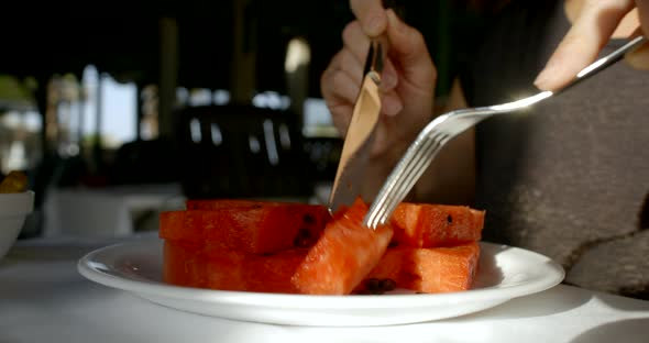 Person Cuts Red Watermelon Slices with Silver Knife and Fork