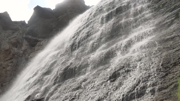 Waterfall with Foamy Water Streams Runs Down Along Rocks