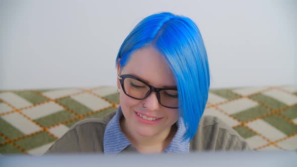 Cute white nerd girl in glasses typing text on notebook computer with cheerful smile in 4k video