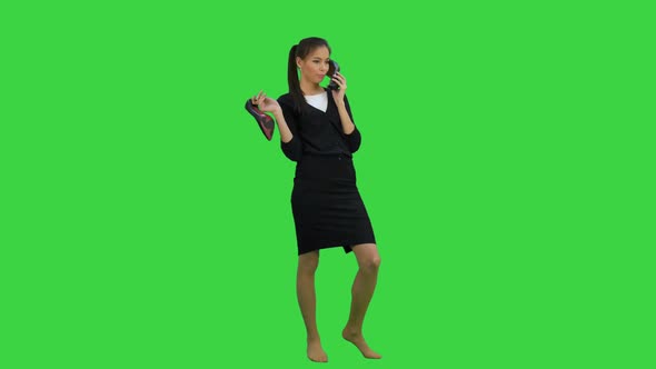 Young Chatty Woman Using a Shoe Like a Telephone on a Green Screen