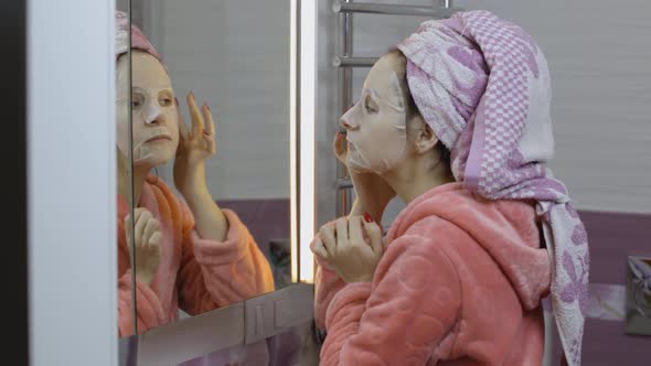 Woman Applying Cosmetic Face Mask in Bathroom. Skincare Spa. Facial Mask