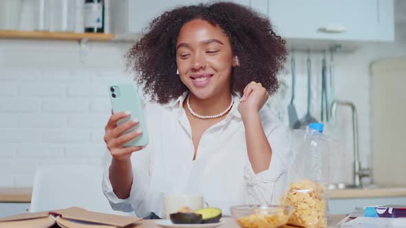 Happy Young African American Woman Waving Hand Greeting Farands Sits at Kitchen