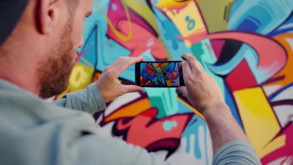 Graffiti artist taking photo of graffiti wall with phone 4k