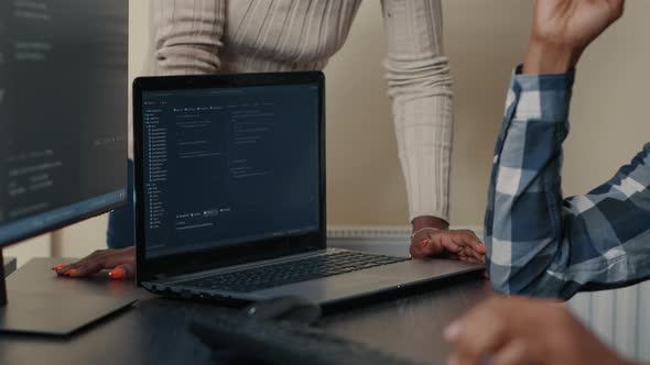 Closeup of Laptop Running Algorithm Parsing Code on Desk in Front of Programmers Doing Team Work