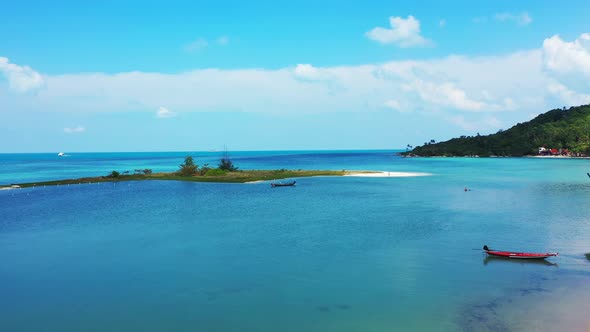 Wide fly over island view of a sandy white paradise beach and aqua blue water background in colourfu