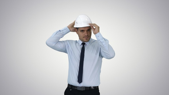 Young construction worker in hard hat on gray background