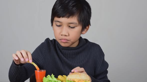 Cute Asian boy eating a delicious french fries