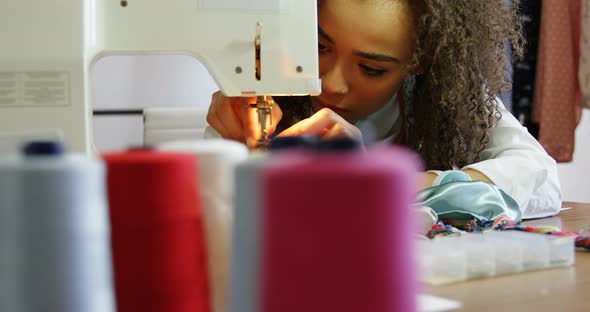 Front view of African American female fashion designer working with sewing machine in workshop 4k