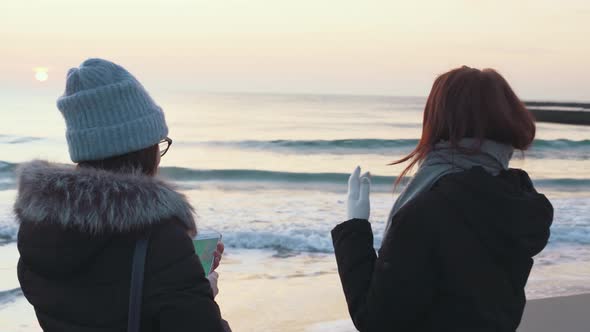 Two Beautiful Girls Have a Good Time at Sea at Sunrise or Sunset