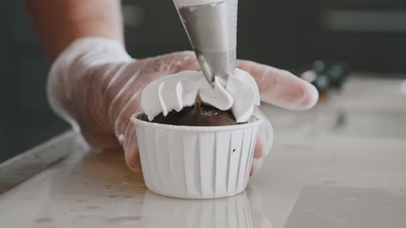 Woman Chef Applying White Cream on the Top of a Cupcake