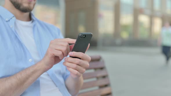 Close Up of Man Using Smartphone While Sitting Outdoor on Bench