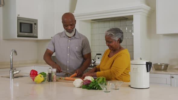 African american senior couple chopping vegetables together in the kitchen at home