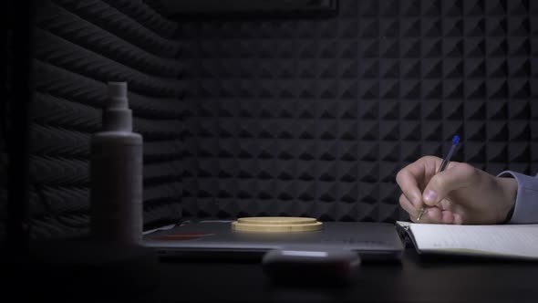 Man writes in notebook on background of black wall