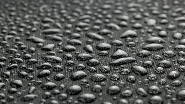 Spinning Closeup Background of Black Hydrophobic Fabric Covered with Water Drops