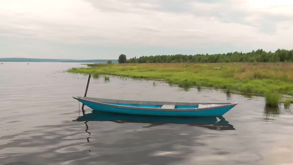 Old Blue Wooden Boat Anchored Off the Coast of the Bay Sways on Calm Waves.