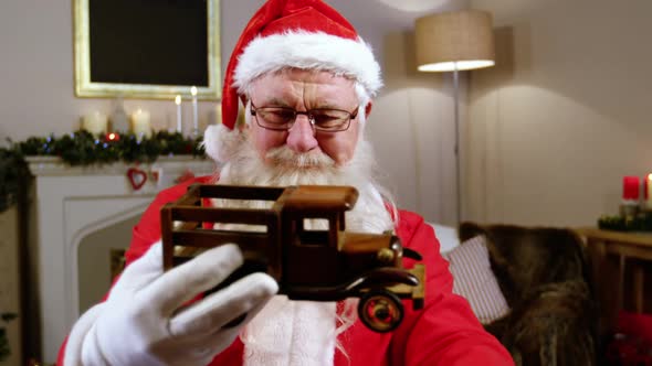 Santa claus holding and looking at a toy car