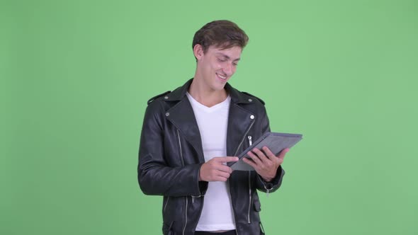 Happy Young Rebellious Man Thinking While Using Digital Tablet