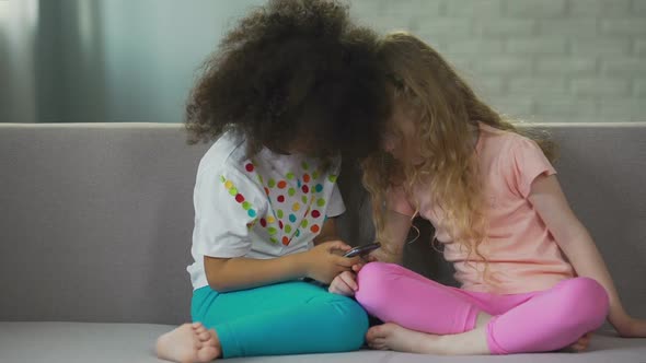 Multi-Ethnic Kids Sitting on Couch and Playing on Smartphone, Modern Technology