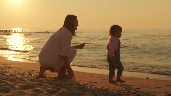 Mom Plays with a Small Child on the Seashore