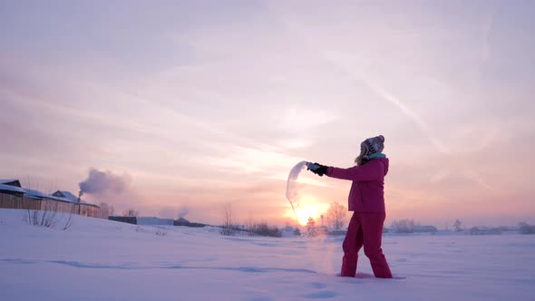Cheerful Girl is Splashing Out the Hot Boiled Water in the Cold Air on a Beautiful Winter Day at