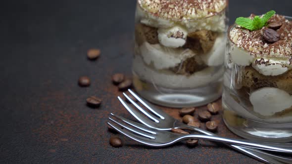 Two Portions Classic Tiramisu Dessert in a Glass on Dark Concrete Background