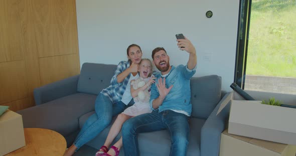 Beautiful Family Making Memorable Selfies on Smartphone While Relaxing, Sitting Between Cardboard