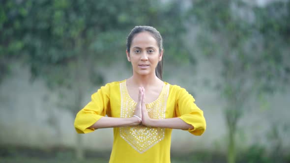 Indian woman doing a Namaste Yoga pose or Namaskarasana in a park