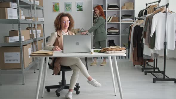 Beautiful Young Woman Working in a Clothing Store Selling Goods Online with a Female Colleague