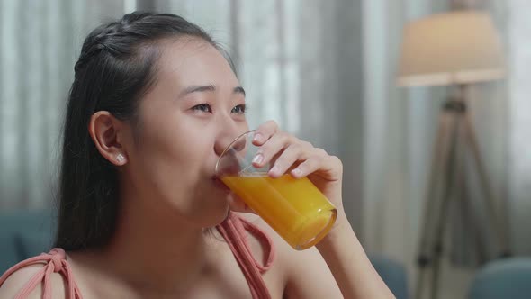 Close Up Of Smiling Asian Woman Enjoys Drinking Orange Juice While Having Healthy Food At Home