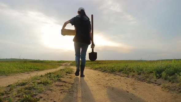 Woman Farmer Holding Shovel in His Hand Walking Across Green Field a Pile of Dirt Soil