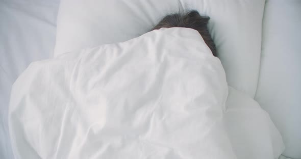 Woman Peeking Under Duvet and Smiling. 