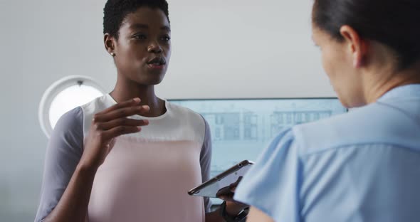 Two diverse businesswoman working and talking in office