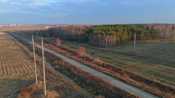 A Drone Flies Over Power Line Wires That Hang Over Agricultural Fields From Which Crops Have Been