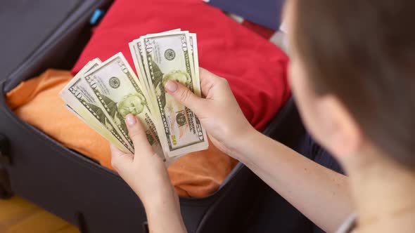 Female hands counting dollar cash banknotes on suitcase background.