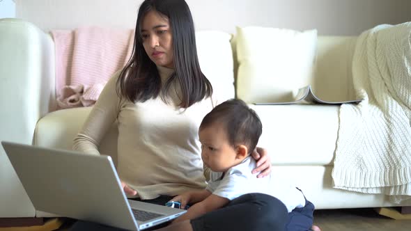 Asian mother working from home while her son playing