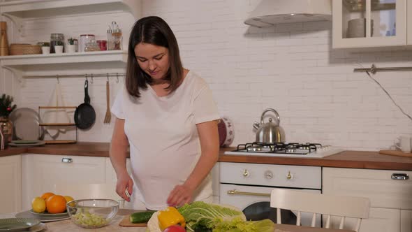 Pregnant Woman Prepares Vegetable Salad in the Kitchen She Cooks and Dances