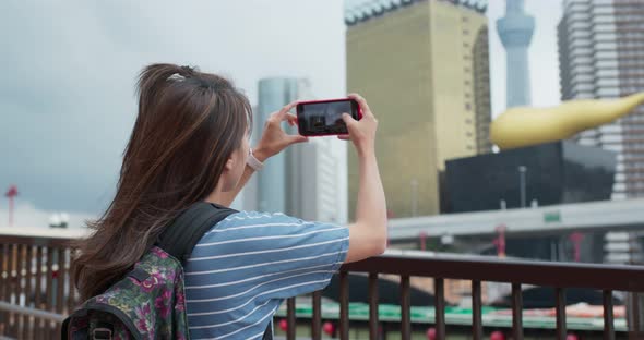Woman travel to tokyo, take photo on cellphone in the city