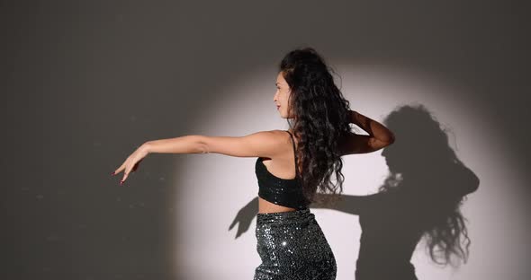 Young Woman with Curly Hair Dancing in a Dark Studio