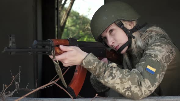 Closeup Woman in Uniform in Zone of Armed Conflict Aims with an Assault Rifle