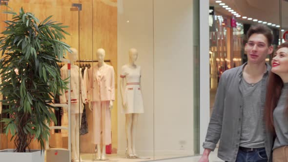 Young Couple Walking at the Shopping Mall, Enjoying Seasonal Sales