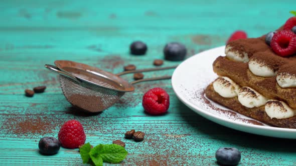 Portion of Classic Tiramisu Dessert with Raspberries and Blueberries on Wooden Background