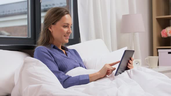 Young Woman with Tablet Pc in Bed at Home Bedroom