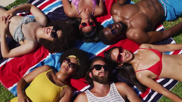 Diverse group of friends sunbathing together and smiling on a sunny day