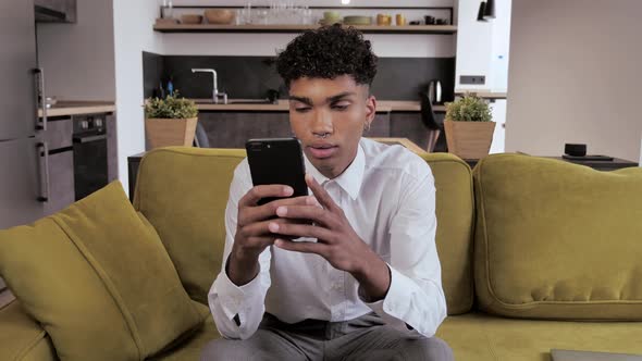 Upset Frustrated Young Black Man Reading Bad News on Smartphone. Sad Guy Using Phone at Home. Tired